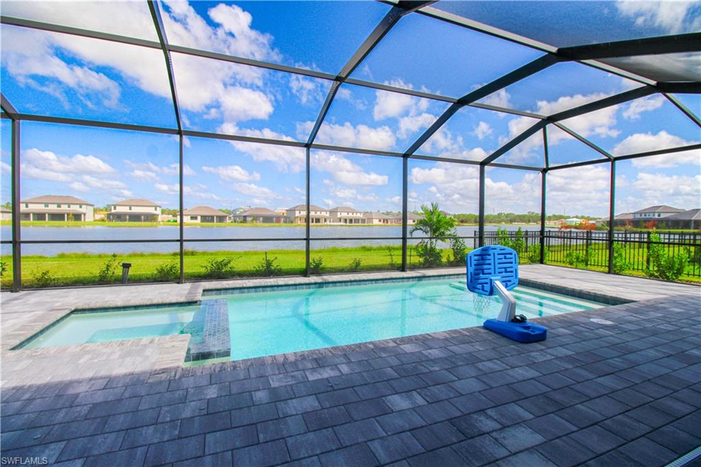 View of swimming pool with a water view, a patio area, and glass enclosure