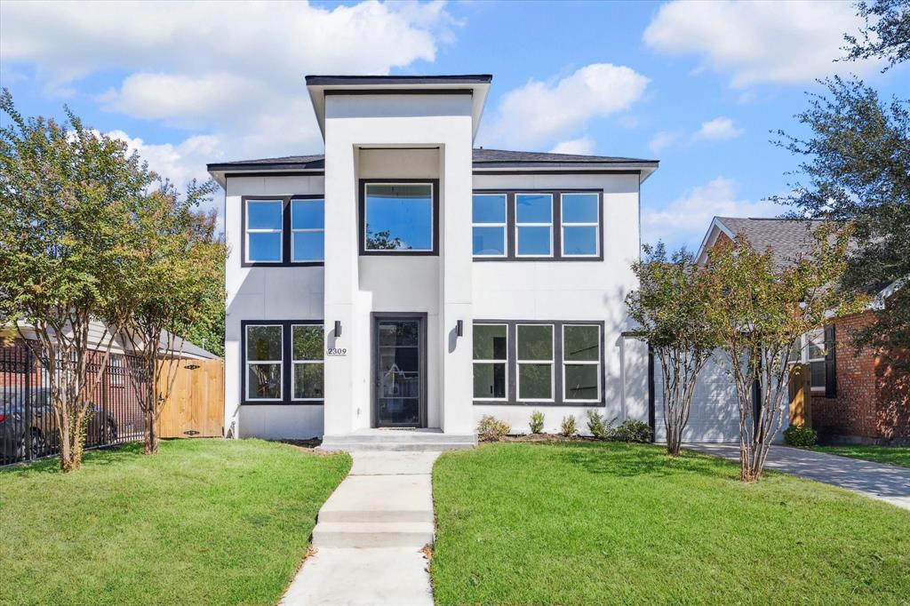 Modern two-story home with a clean, geometric design, featuring large windows for ample natural light, a fenced backyard, and a welcoming entryway.