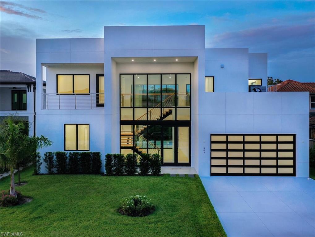 Modern home featuring a garage, a balcony, and a lawn