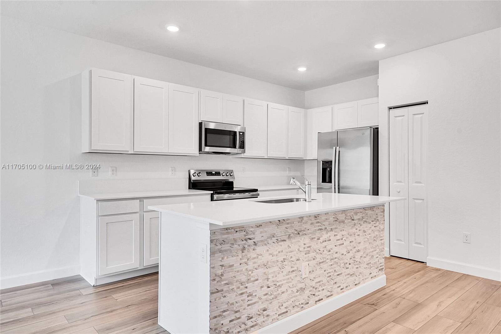 a kitchen with a refrigerator a microwave a sink and cabinets