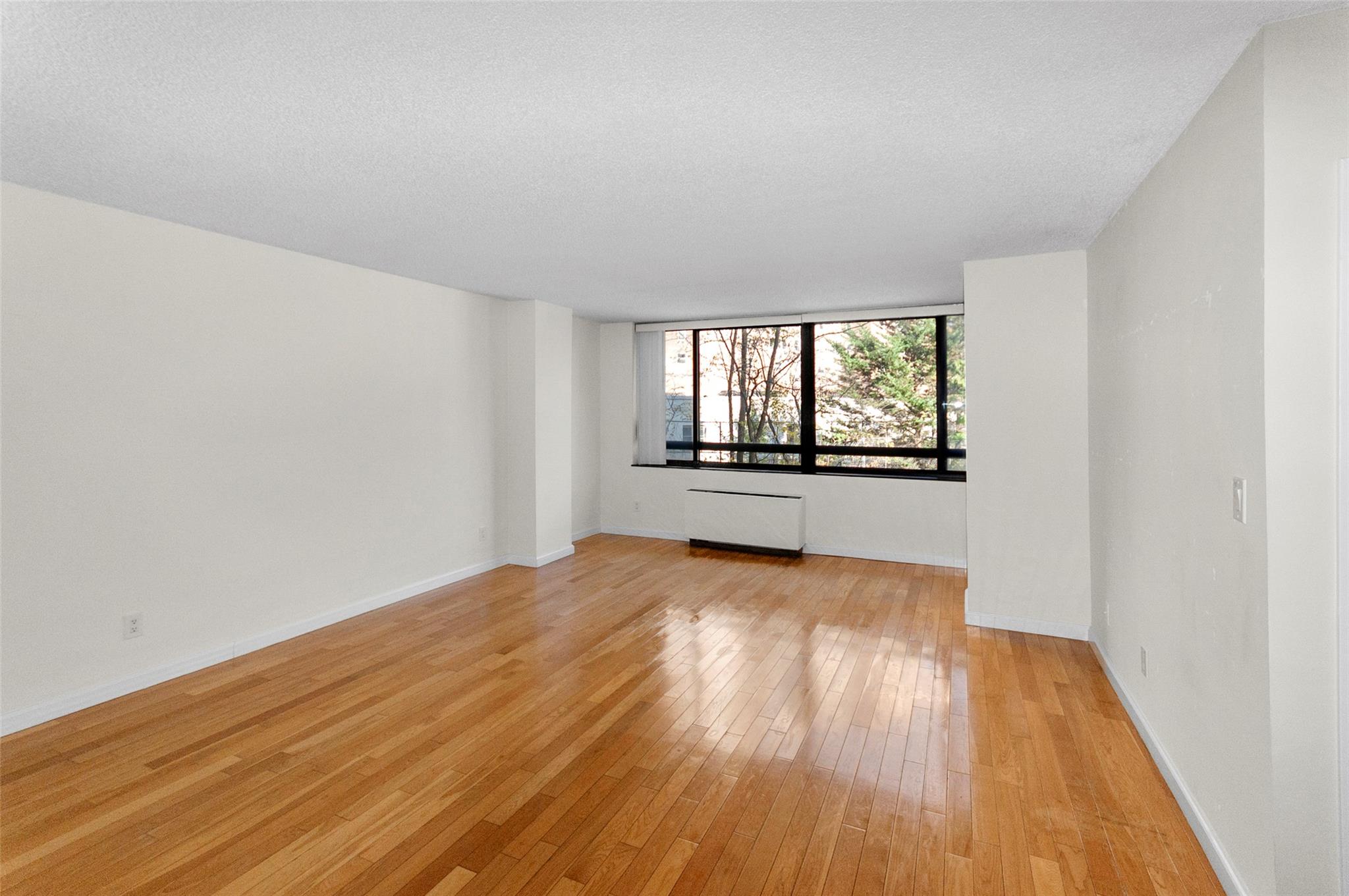 Spare room with light wood-type flooring, radiator heating unit, and a textured ceiling