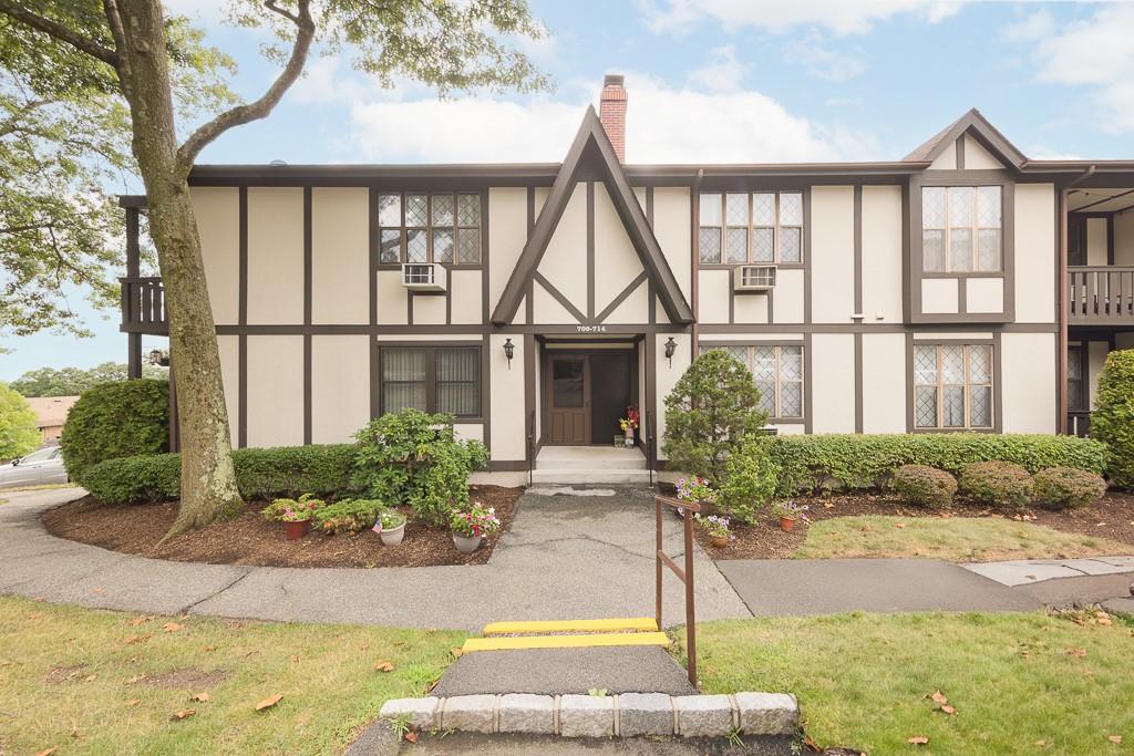 Tudor home featuring a balcony and a front yard