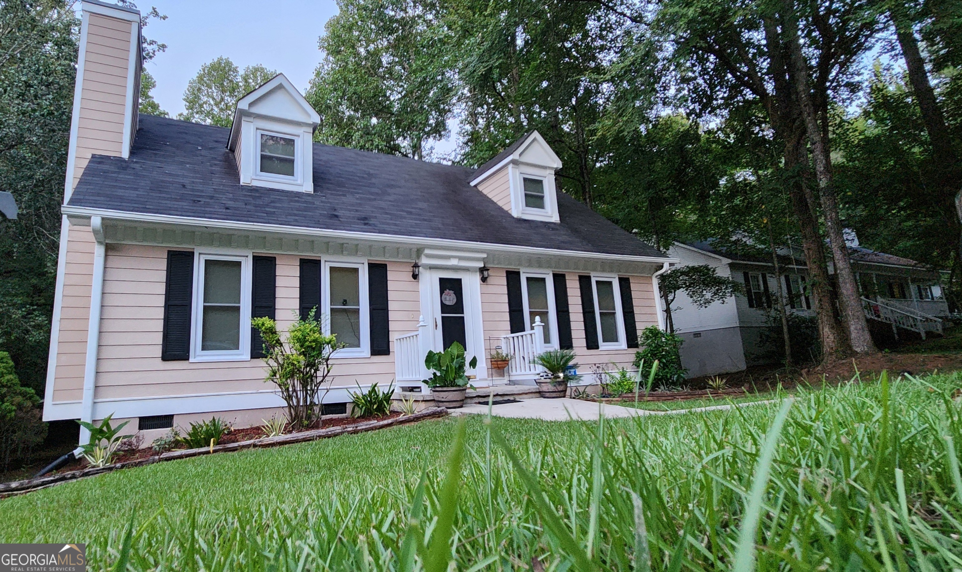 a front view of a house with a yard and potted plants