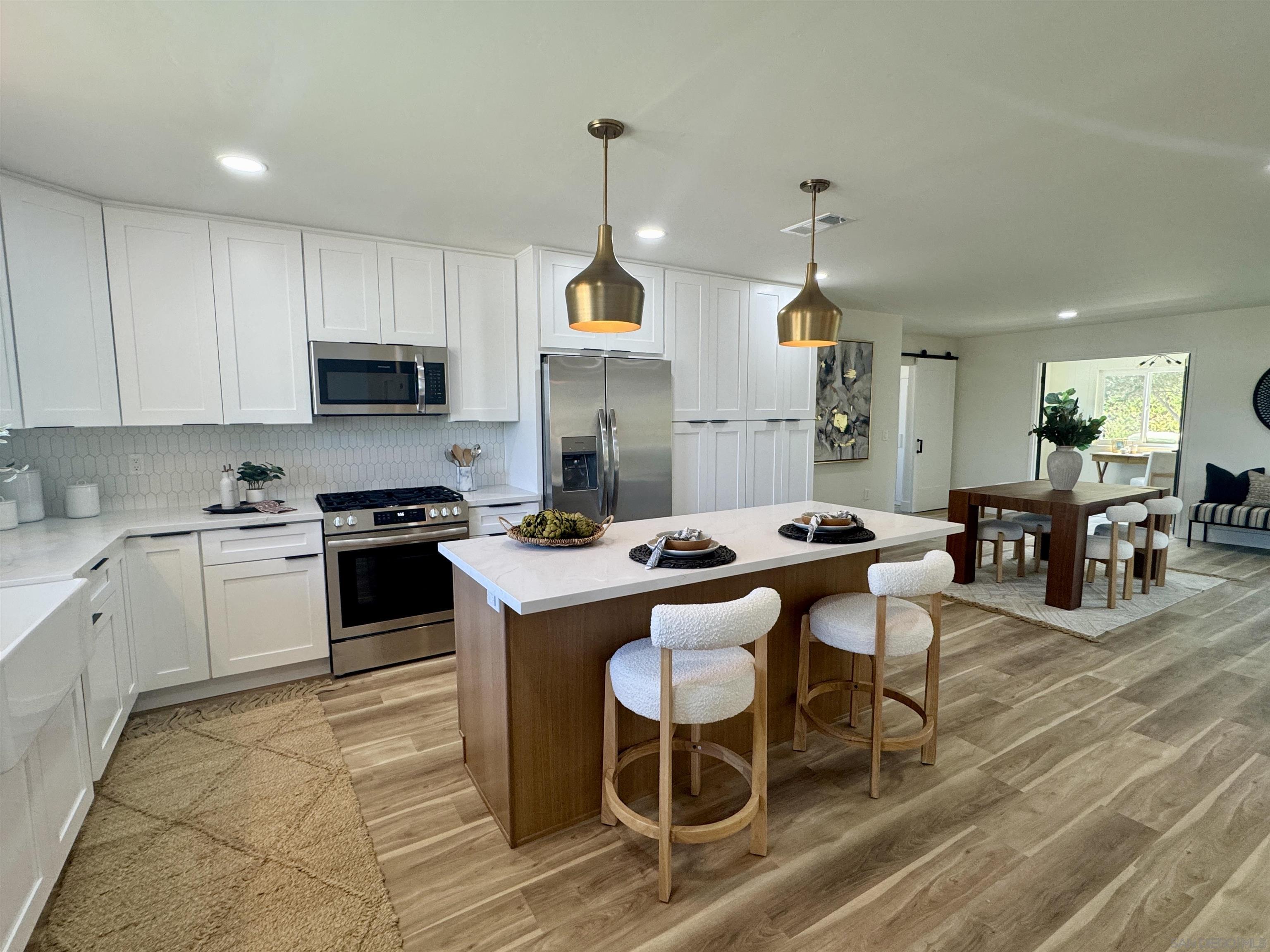 a kitchen with stainless steel appliances kitchen island granite countertop a sink a stove a table and chairs