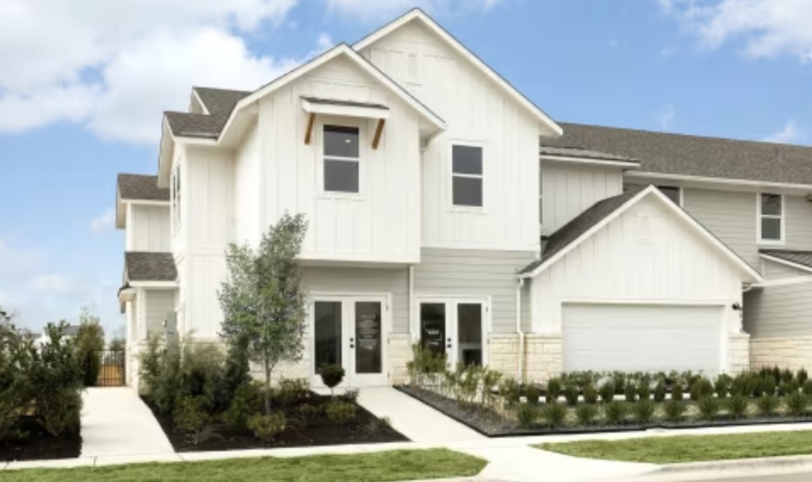 a view of a white house next to a yard