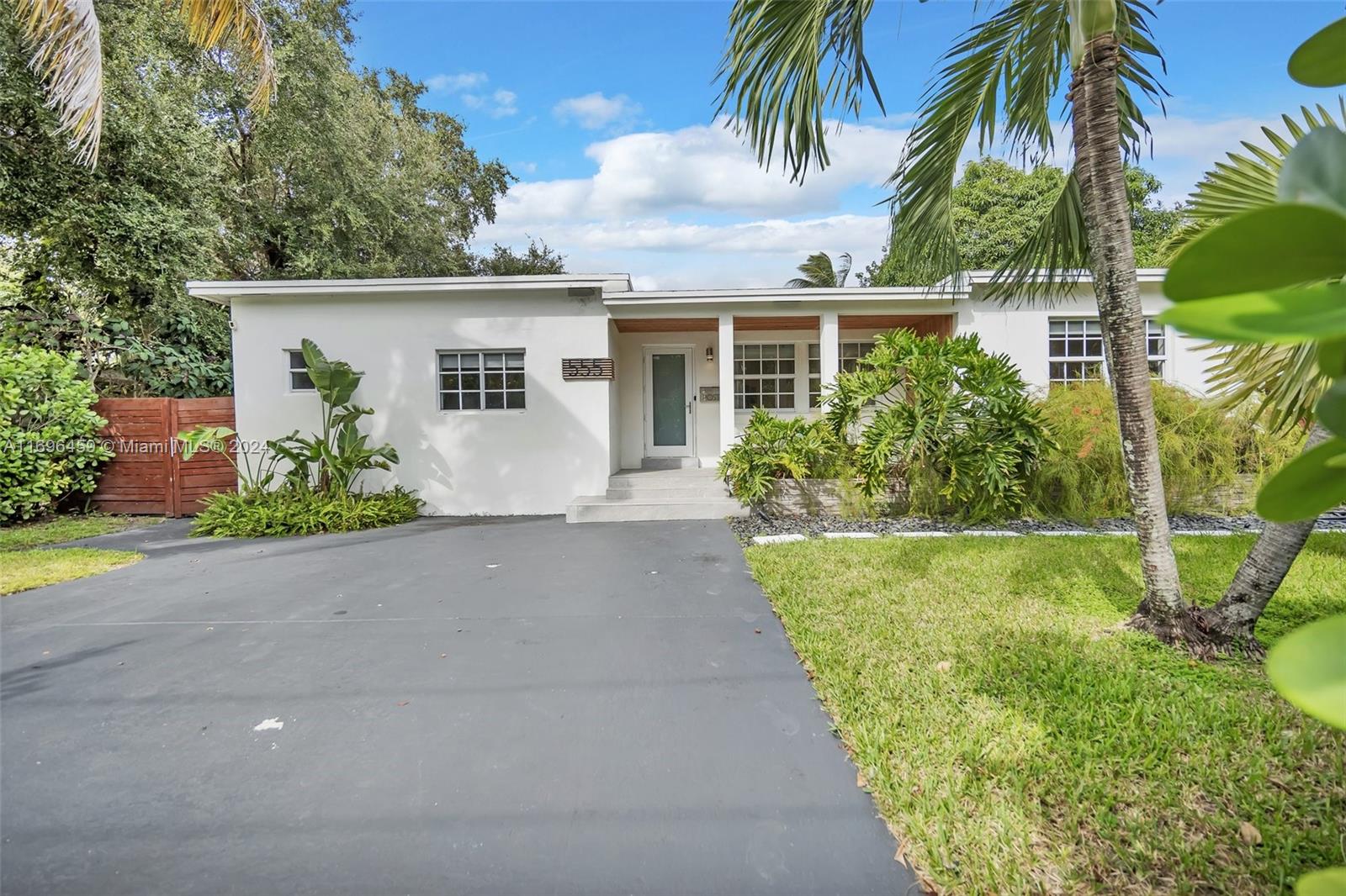 front view of house with a yard and palm trees