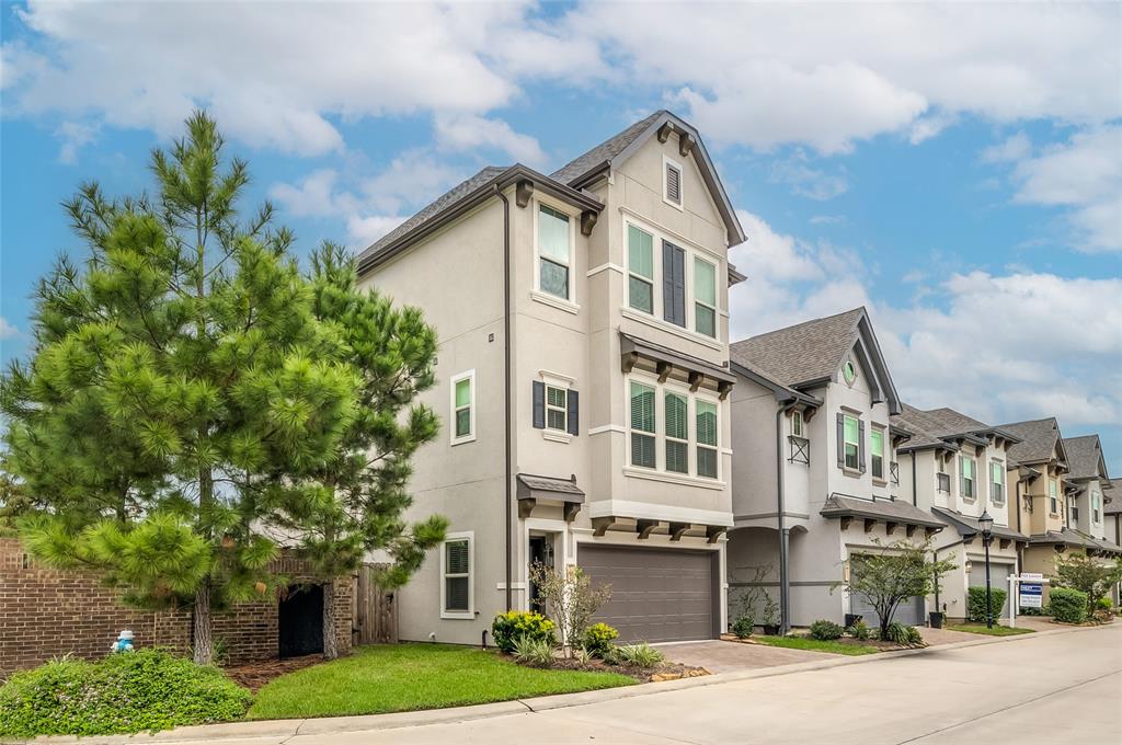 This modern three-story townhouse has a two-car garage, features a neutral color palette and multiple windows that provide an abundance of natural light. The property includes well-maintained landscaping and is situated on a corner lot.