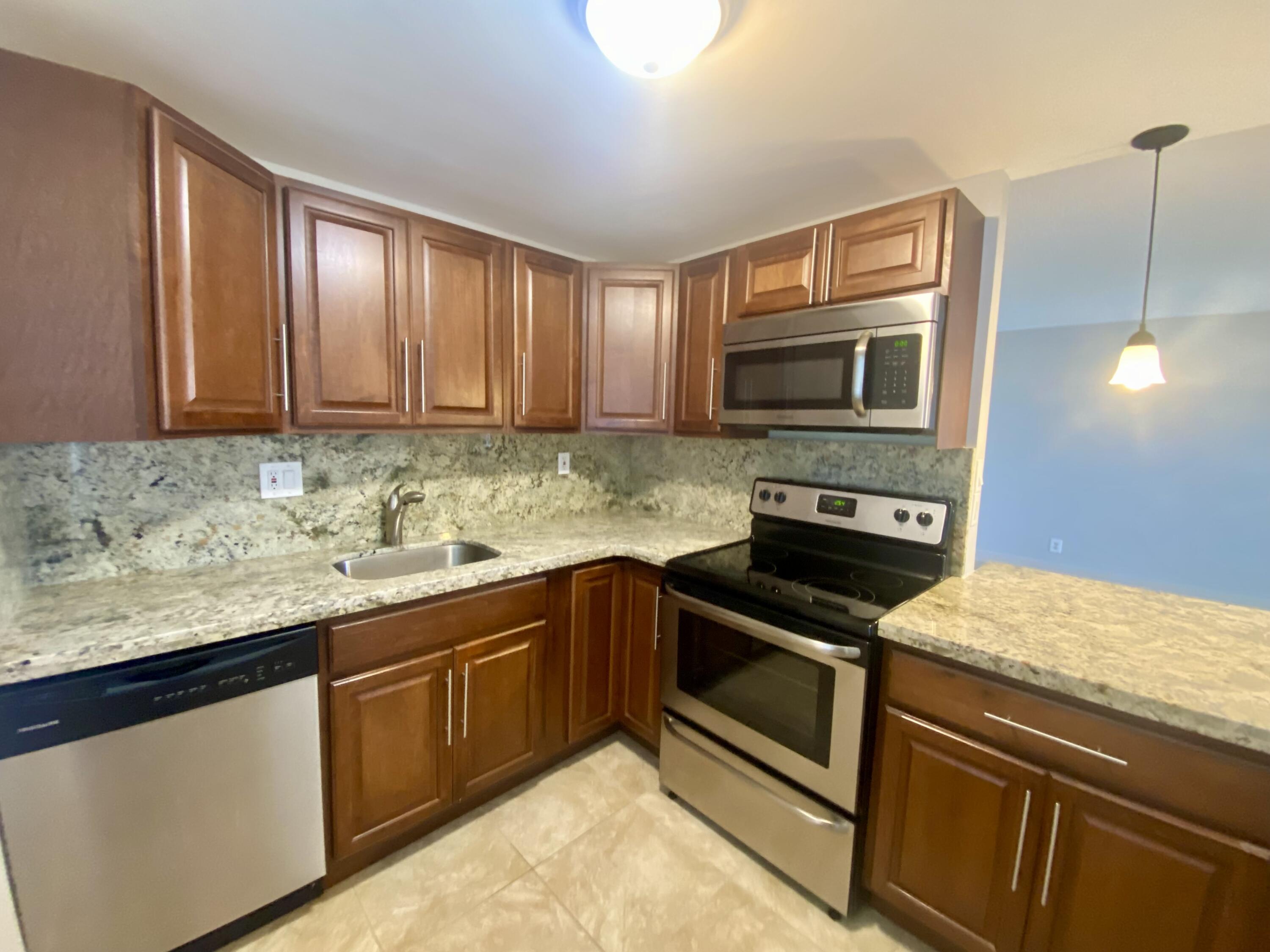 a kitchen with granite countertop cabinets stainless steel appliances and a sink