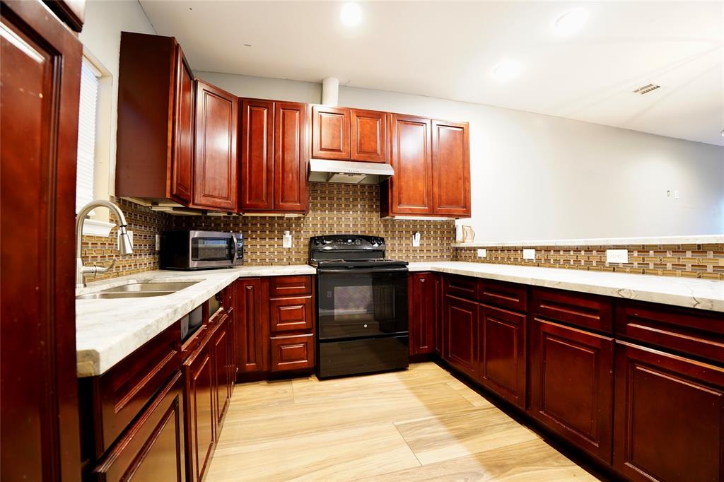 a kitchen with granite countertop wooden cabinets and a stove top oven