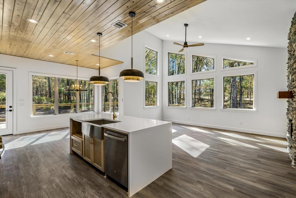 a living room with kitchen island granite countertop wooden floor and large window