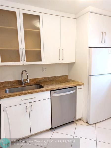 a kitchen with granite countertop white cabinets and a sink