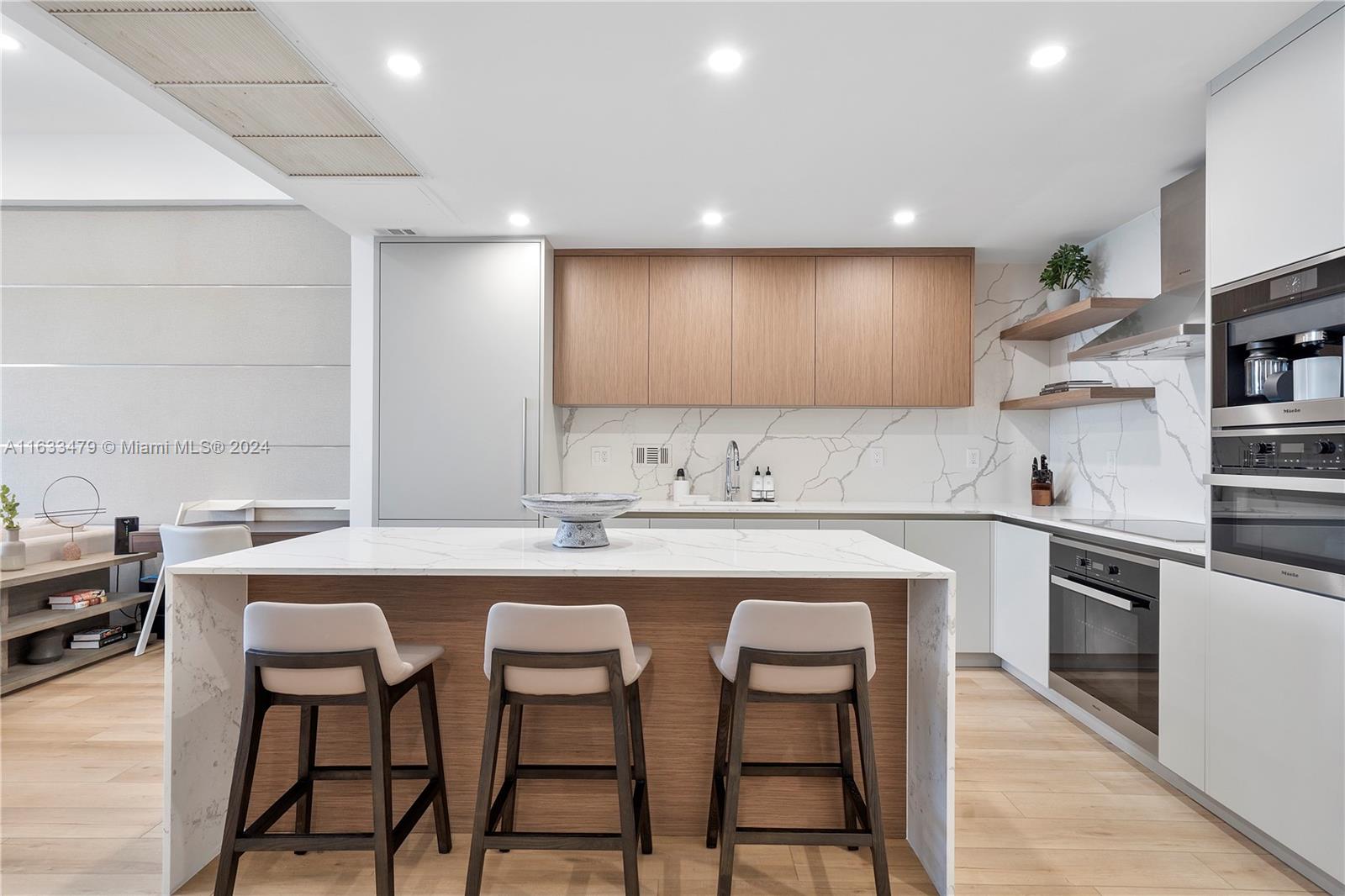 a kitchen with cabinets a sink dishwasher a stove and chairs with wooden floor