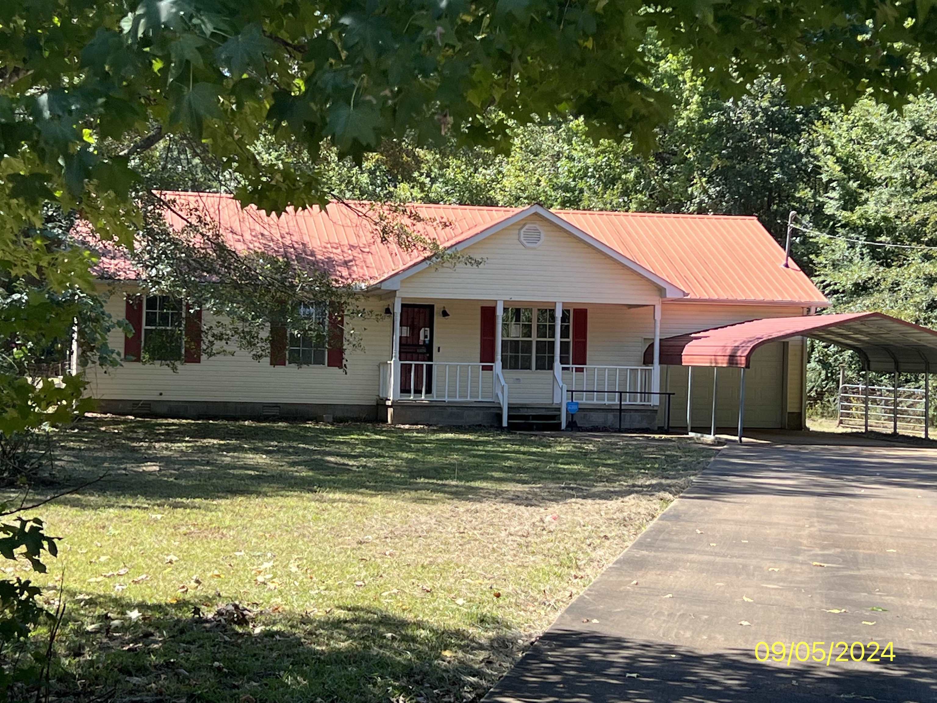 View of front of home featuring a porch, a front lawn, and a carport