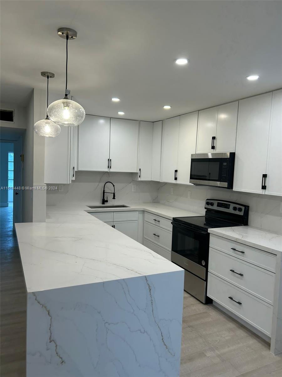 a kitchen with kitchen island granite countertop a sink a counter top space appliances and cabinets