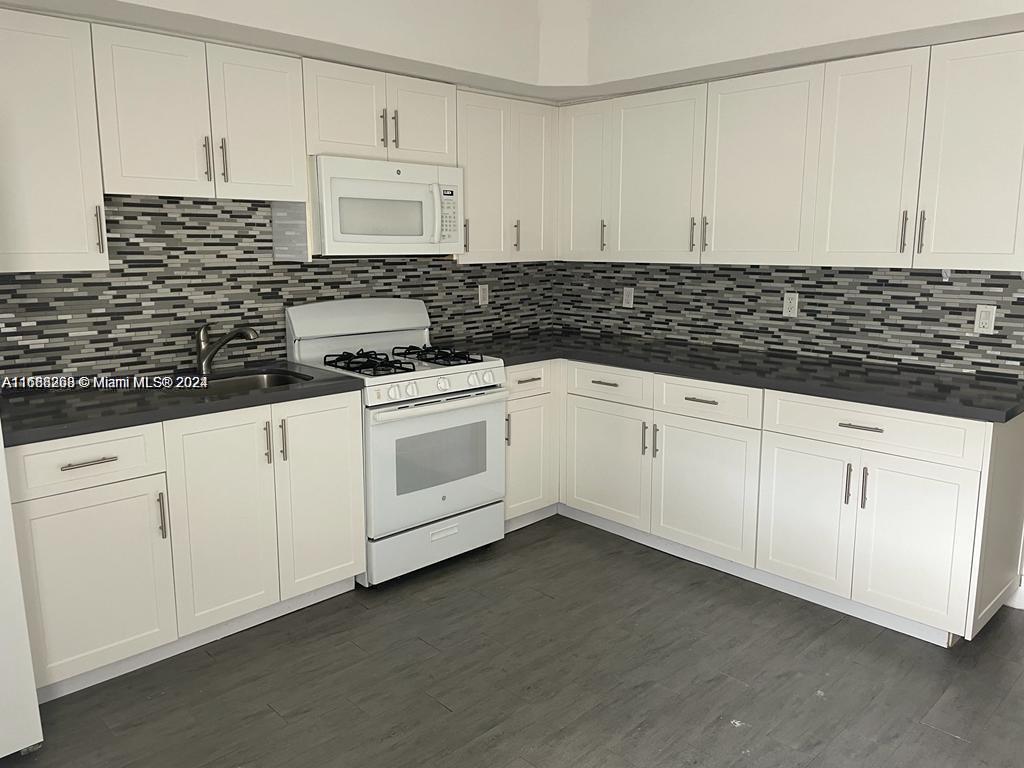 a kitchen with granite countertop white cabinets and white appliances