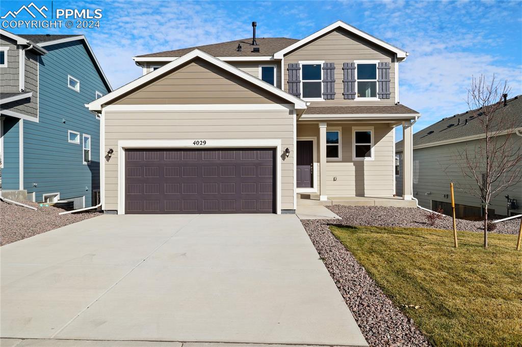 View of front of property with a garage and a front lawn