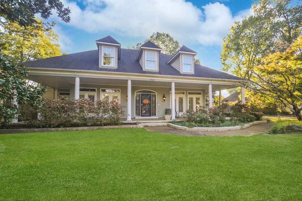 Cape cod home with covered porch and a front lawn