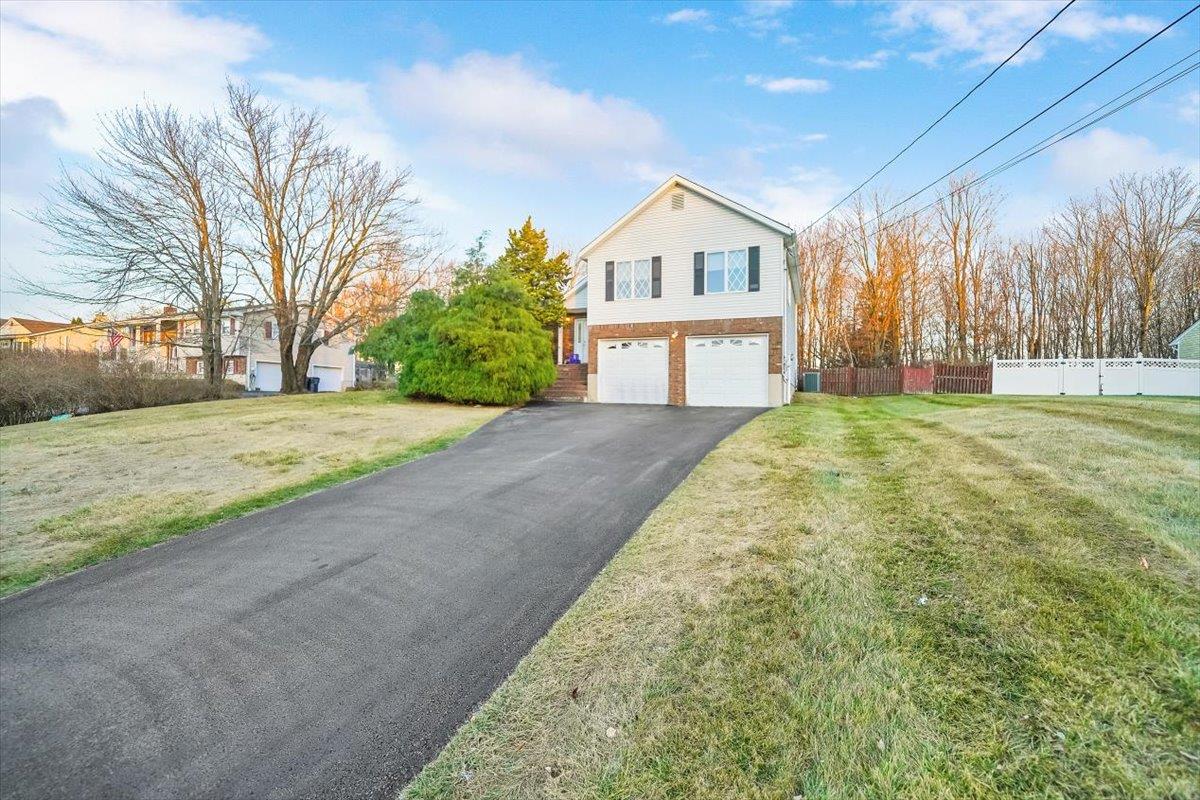 View of property exterior featuring a lawn and a garage