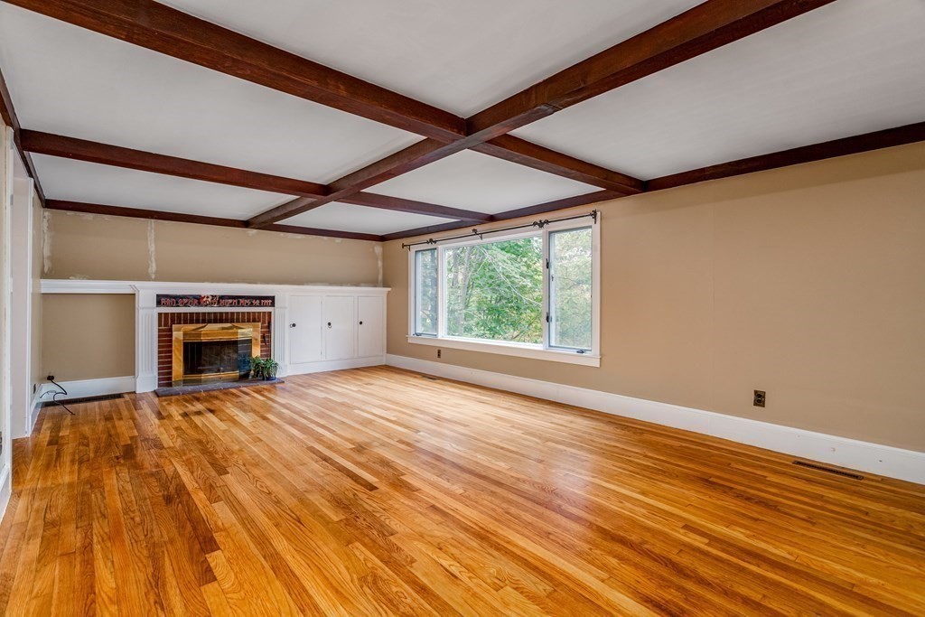 a view of empty room with wooden floor and fireplace