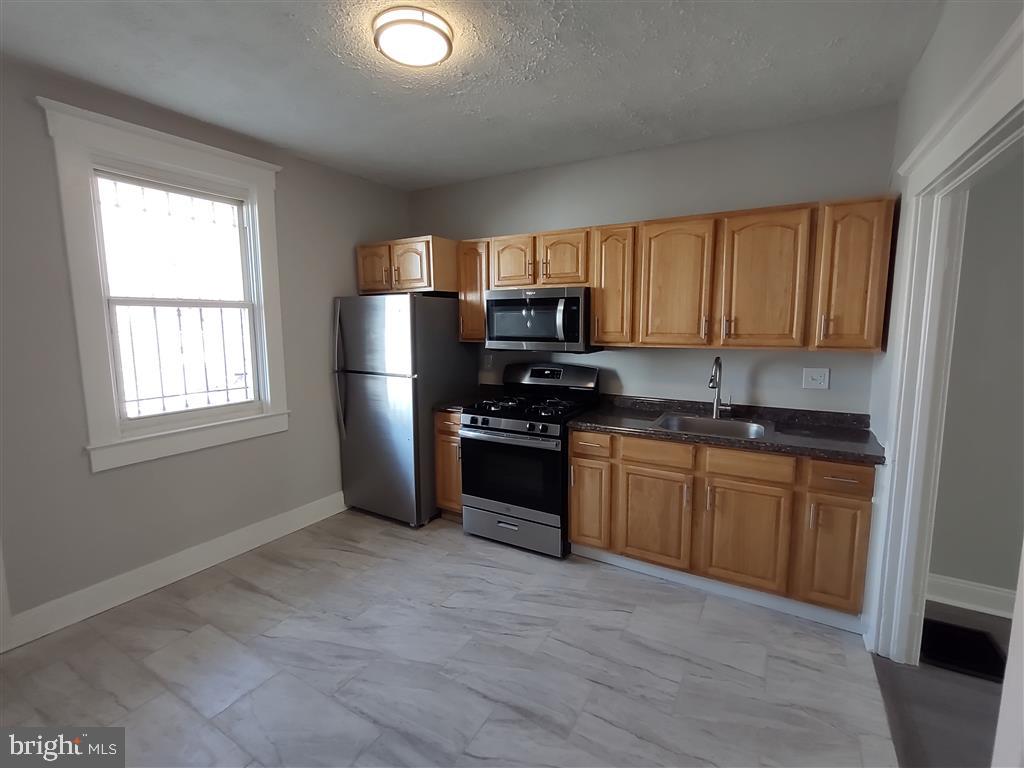 a kitchen with granite countertop a refrigerator stove top oven and sink