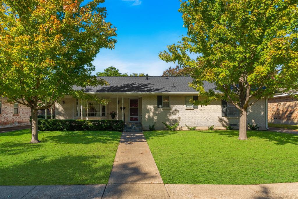 a front view of a house with garden and trees