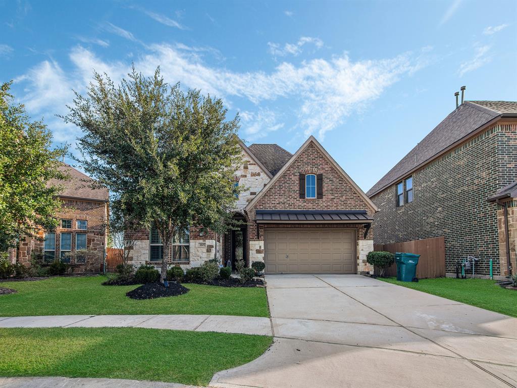 This is a single-family, brick-faced home featuring a pitched roof and an attached two-car garage. The well-manicured lawn is complemented by mature landscaping.