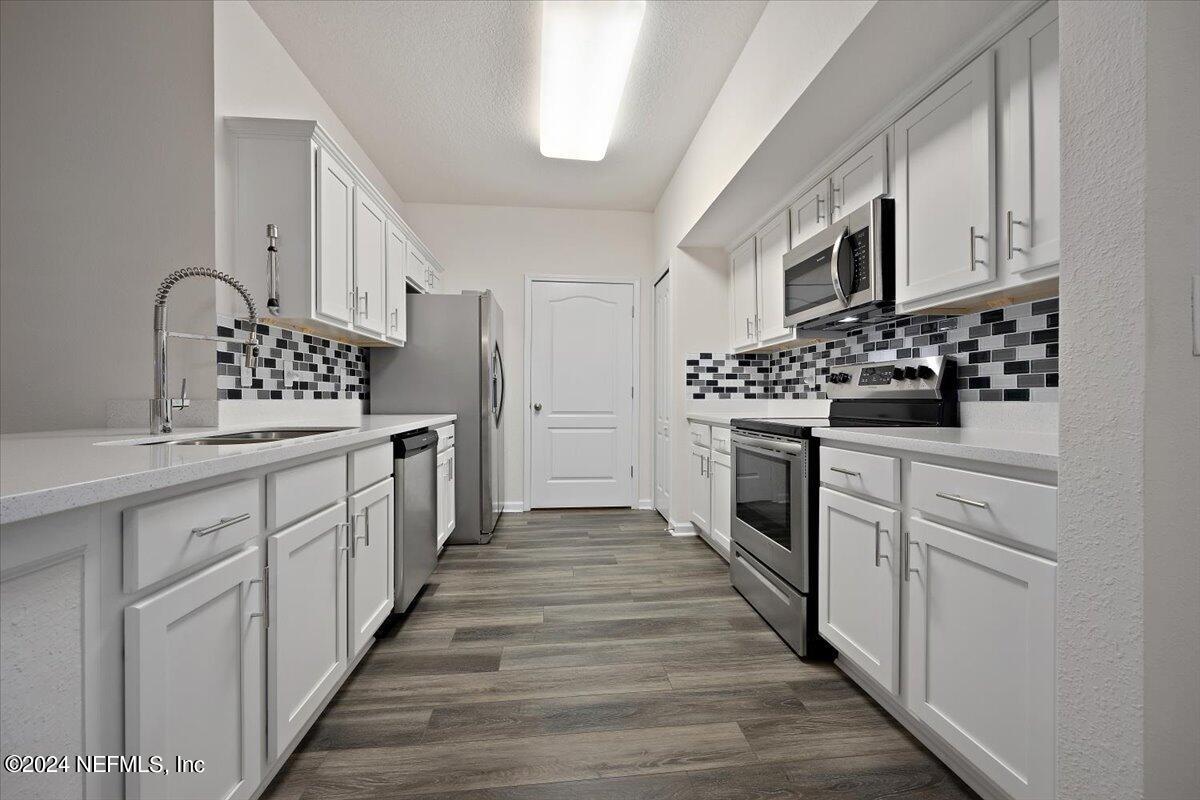 a kitchen with stainless steel appliances a white cabinets and a stove top oven