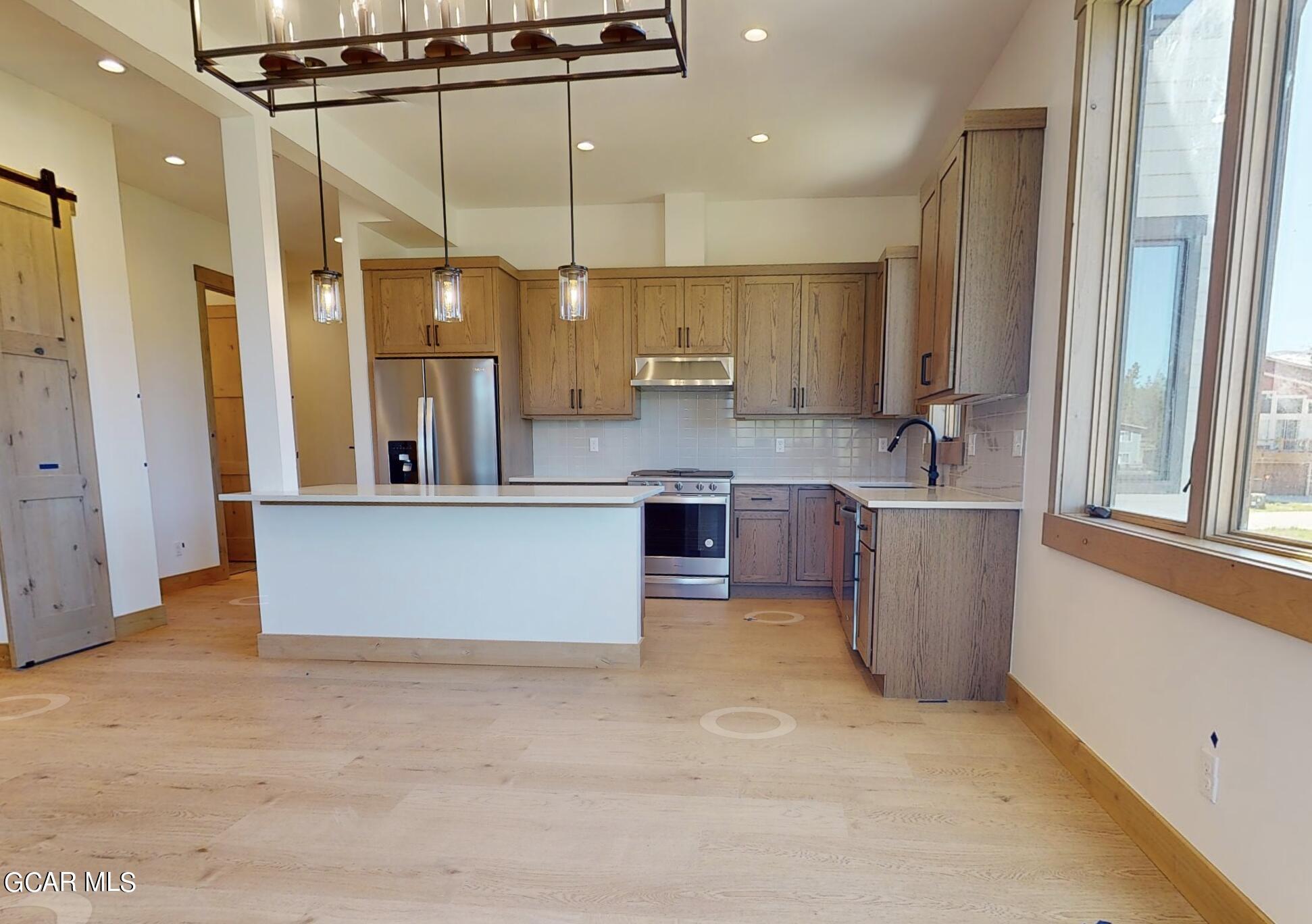 a large kitchen with a large counter top a sink stainless steel appliances and cabinets