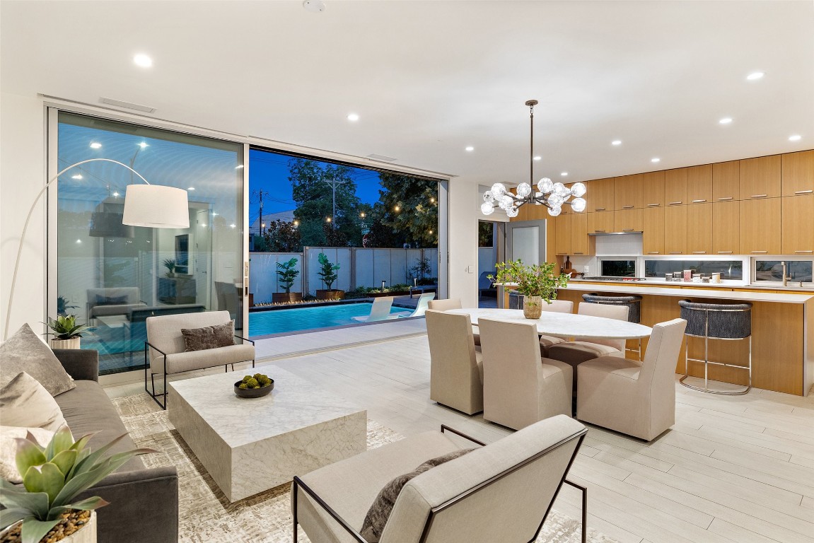 a living room with stainless steel appliances furniture a rug and a chandelier