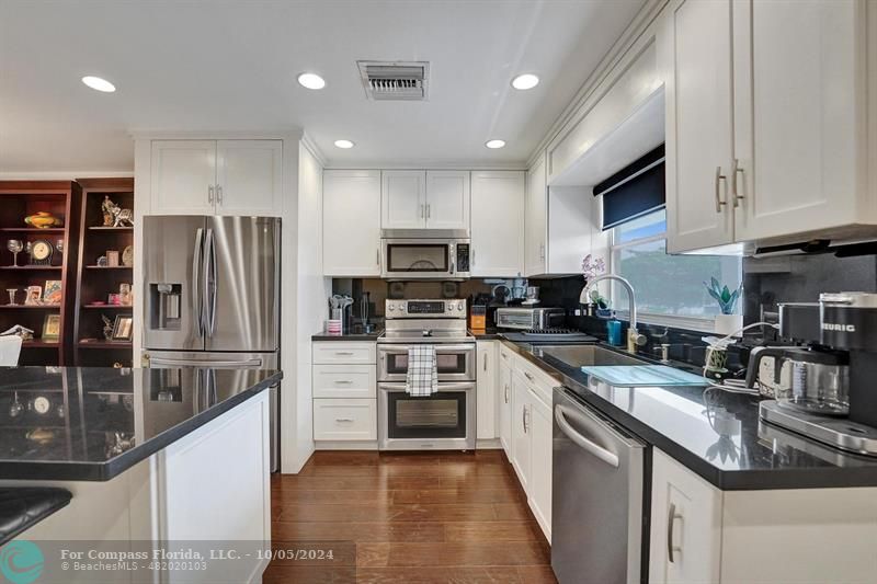 a kitchen with kitchen island granite countertop stainless steel appliances and cabinets