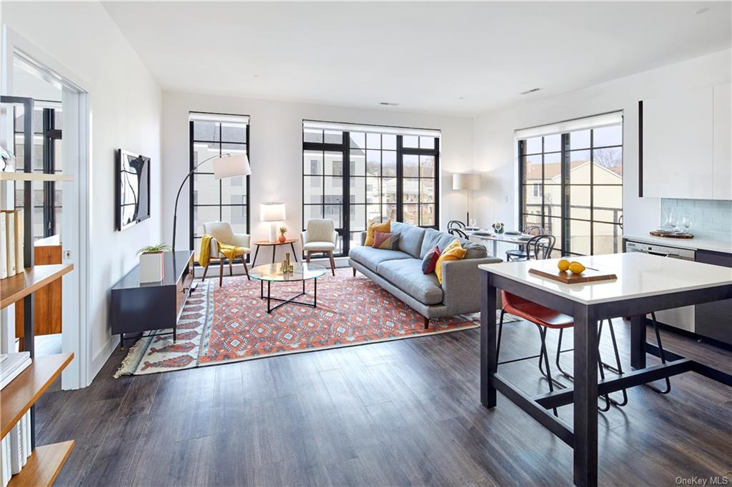 a living room with furniture a rug wooden floor and a floor to ceiling window