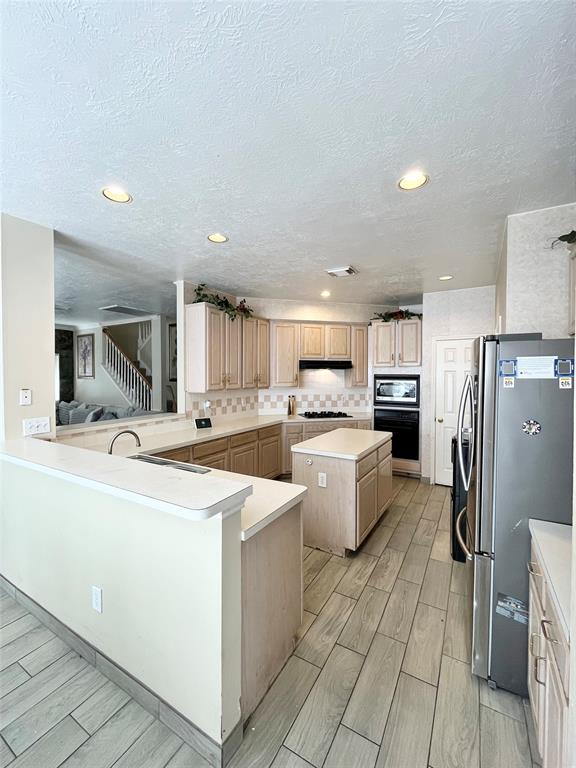 a large kitchen with kitchen island a sink a stove a refrigerator and a cabinets