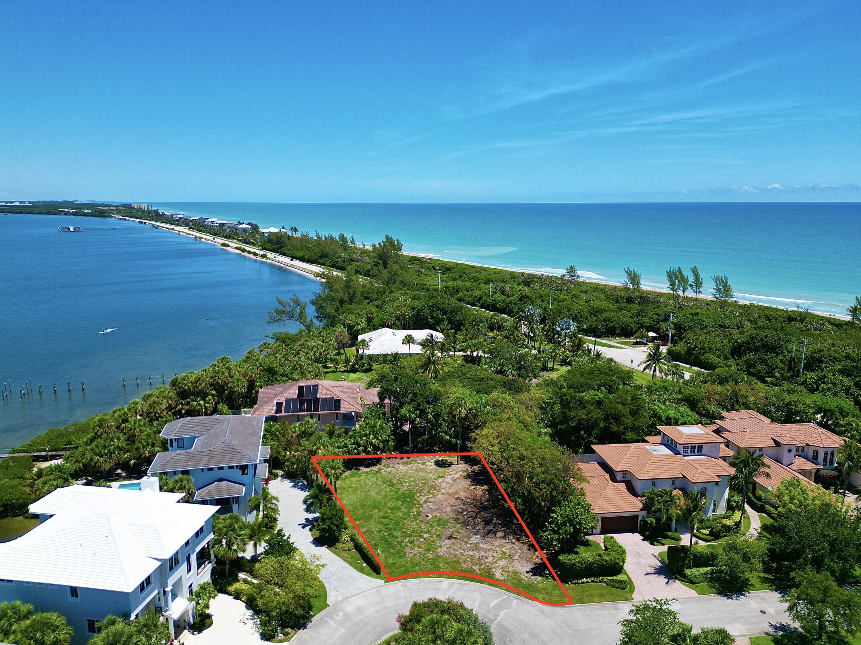 an aerial view of ocean and residential houses with outdoor space