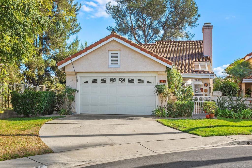 a view of a house with a yard plants and large tree