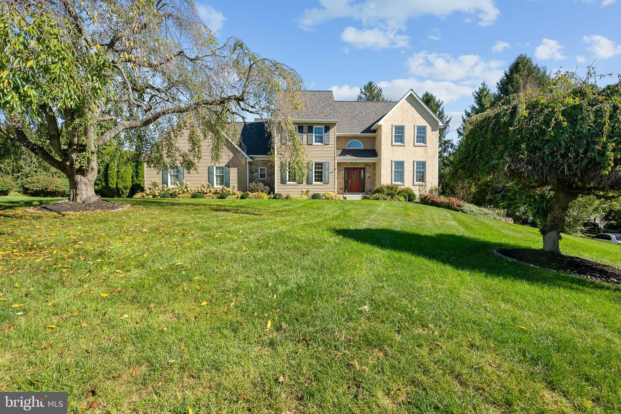 a view of a white house next to a yard with big trees