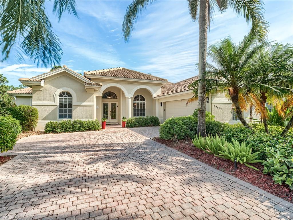 a view of a grey house with a yard and palm trees