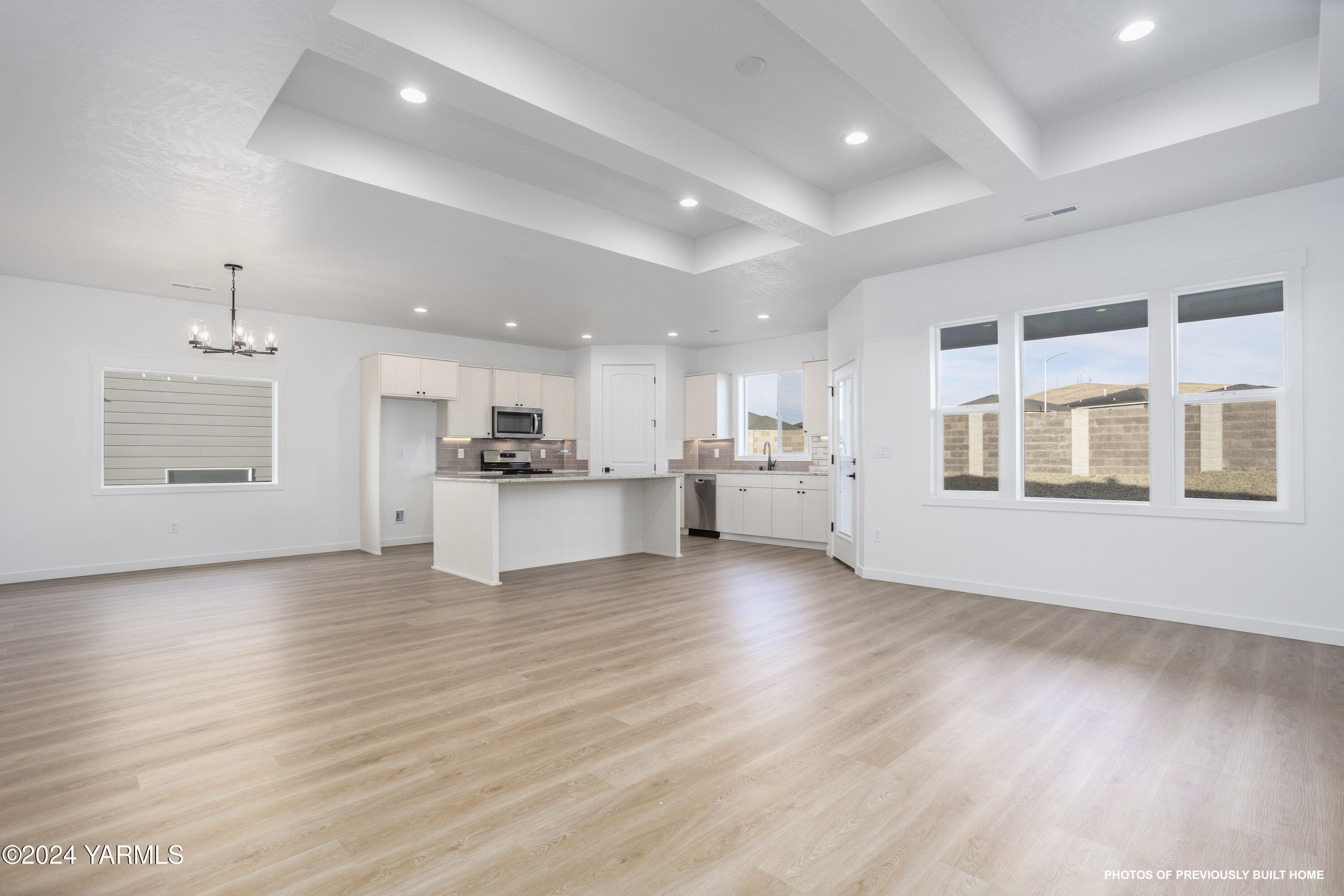 a view of an empty room with kitchen and window