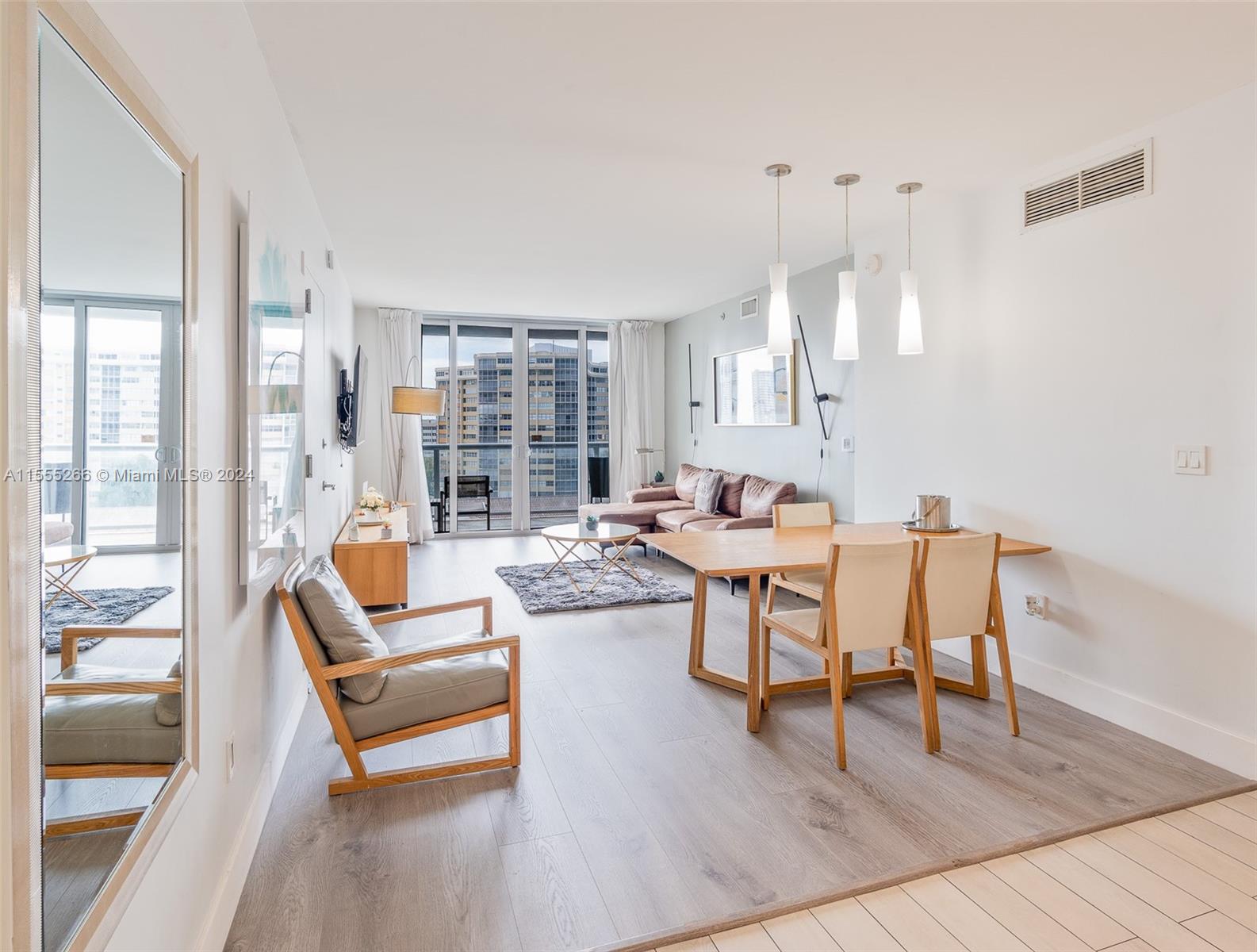 a dining room with wooden floor and large windows