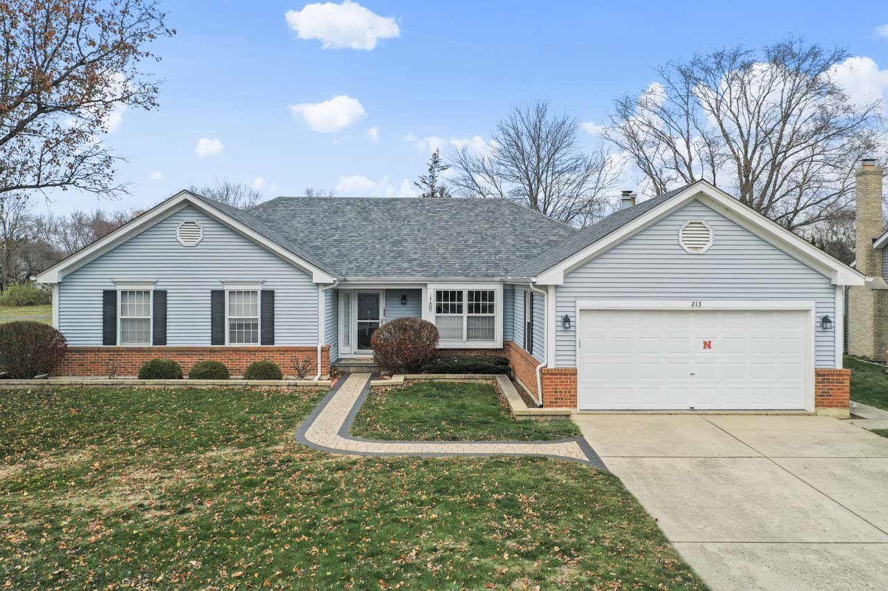 a front view of house with yard and trees in the background