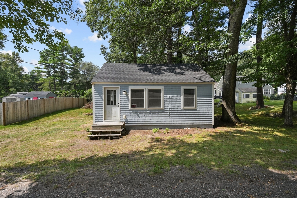 a backyard of a house with a tree and wooden fence