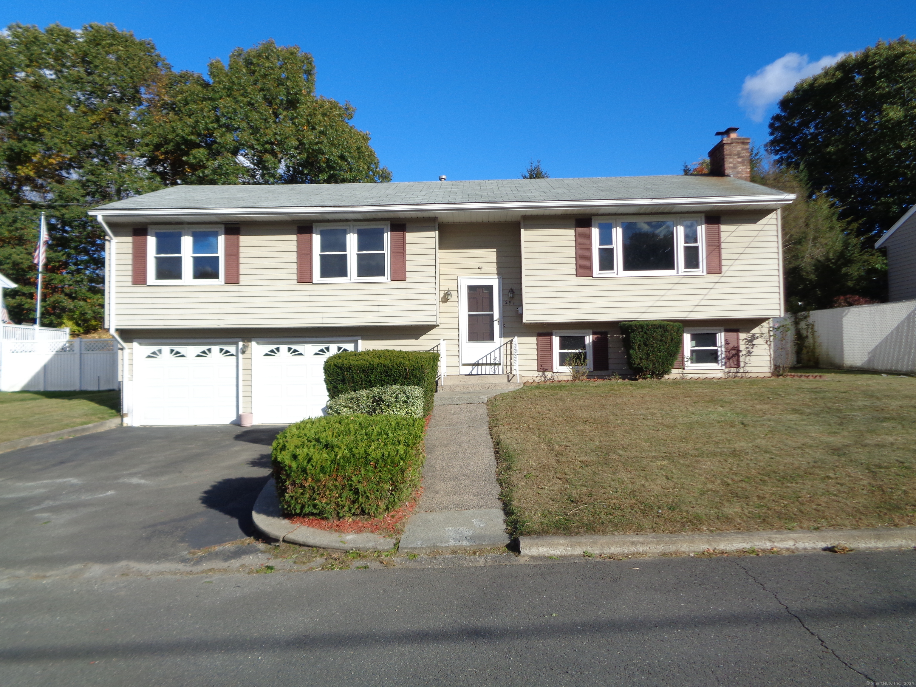 a front view of a house with garage and plants