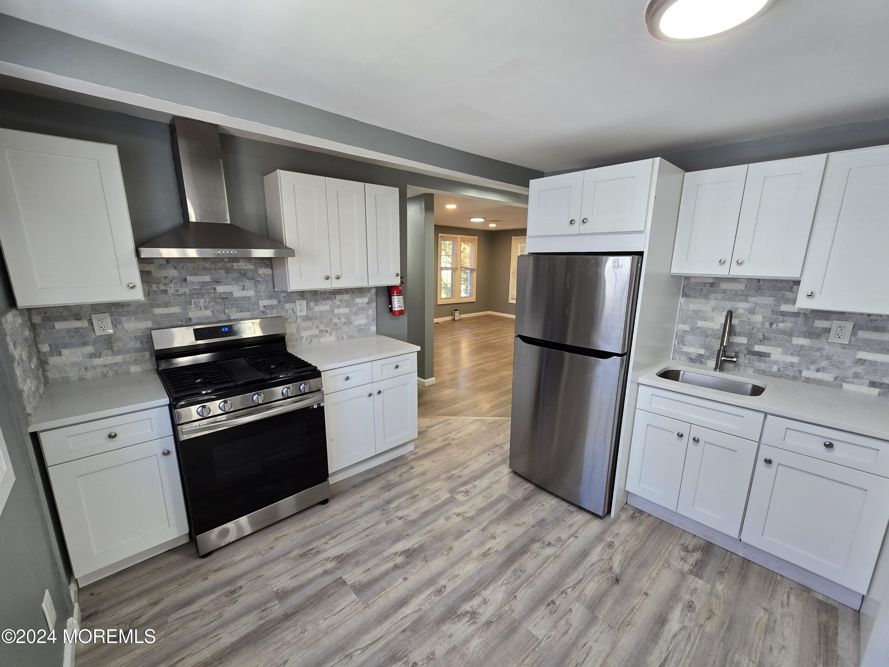 a kitchen with granite countertop a refrigerator stove top oven and sink