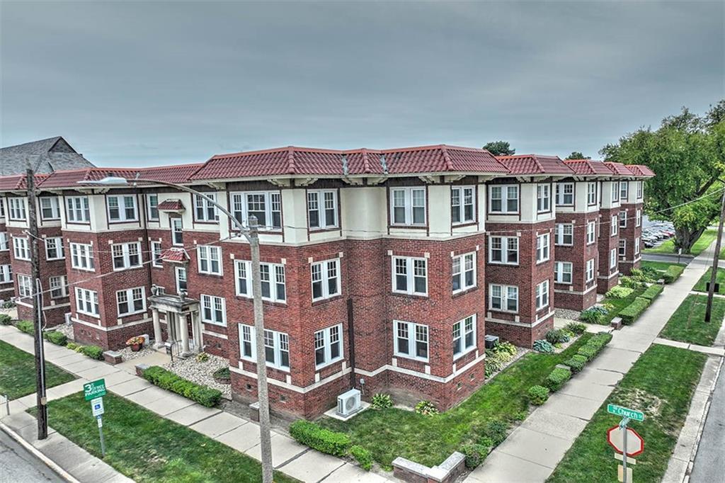 a front view of a residential apartment building with a yard and potted plants