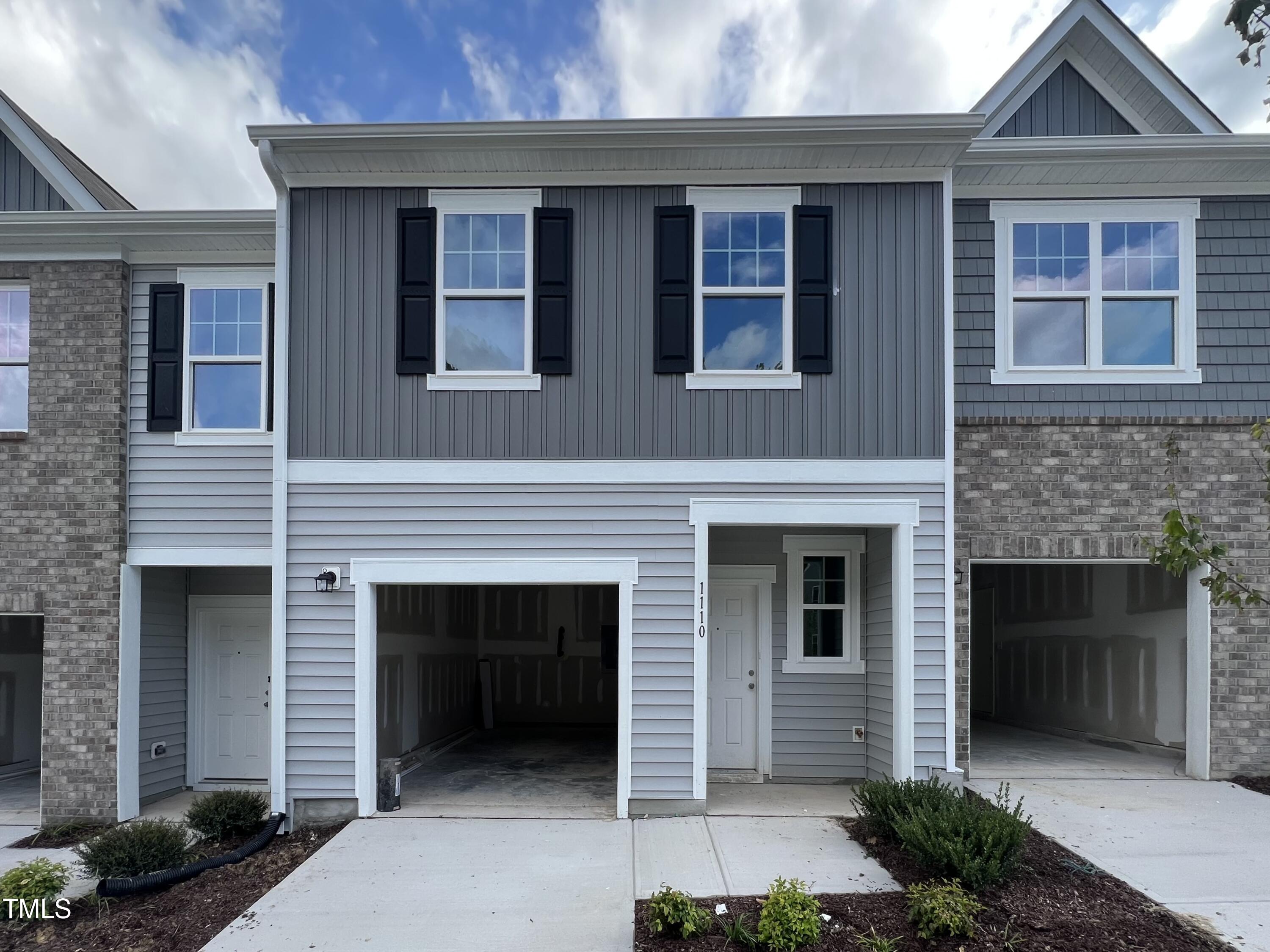 a front view of a house with yard and parking