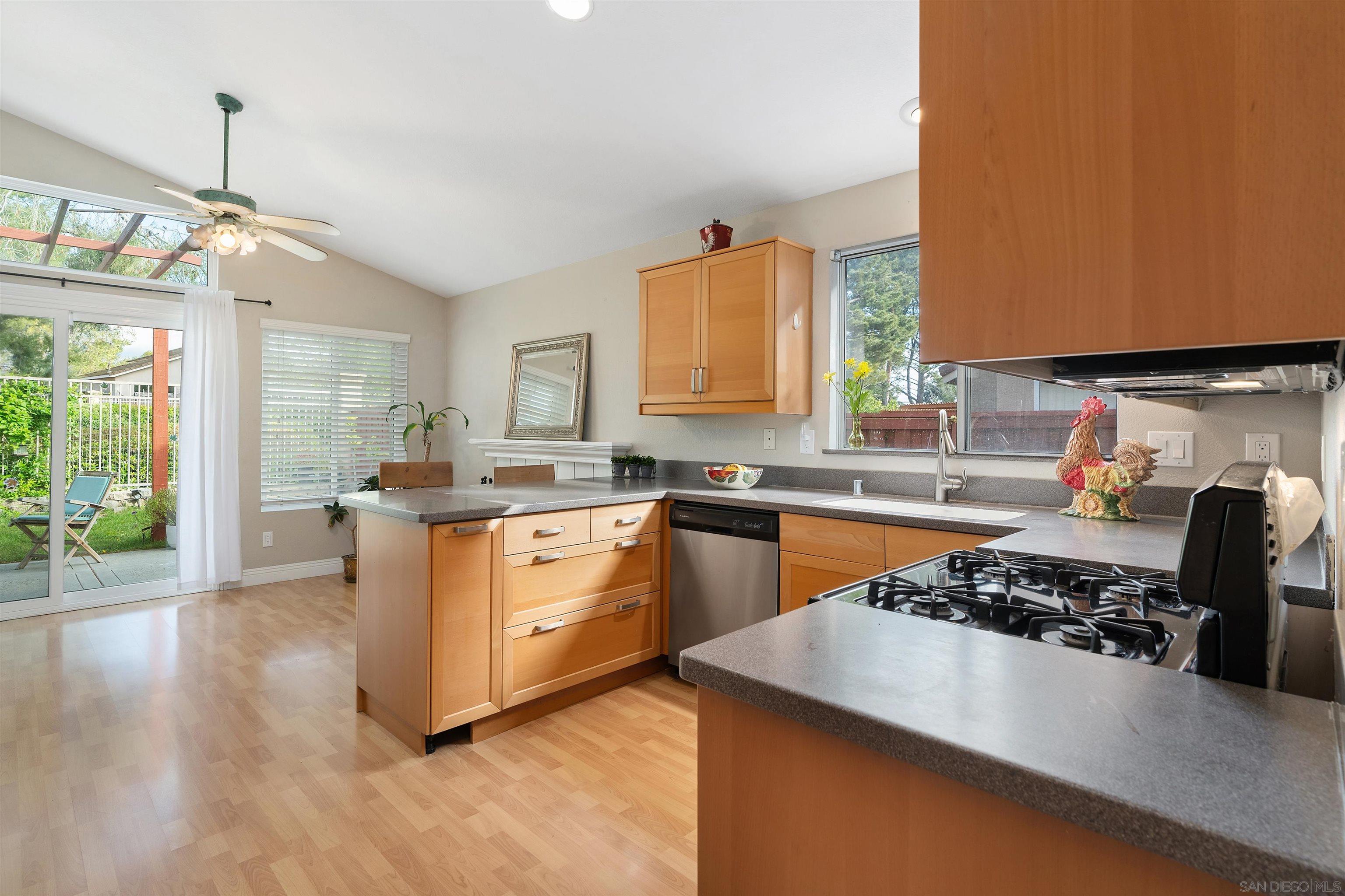 a kitchen with a stove a sink wooden floor and a window