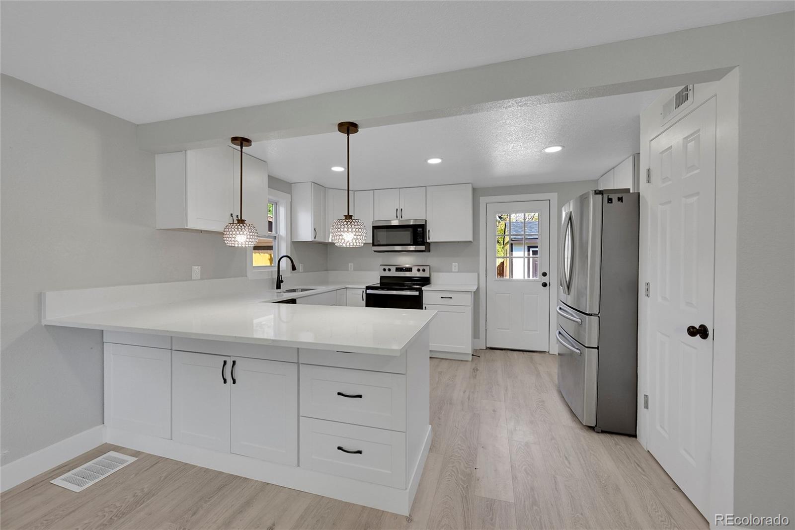 a kitchen with stainless steel appliances a refrigerator sink and white cabinets