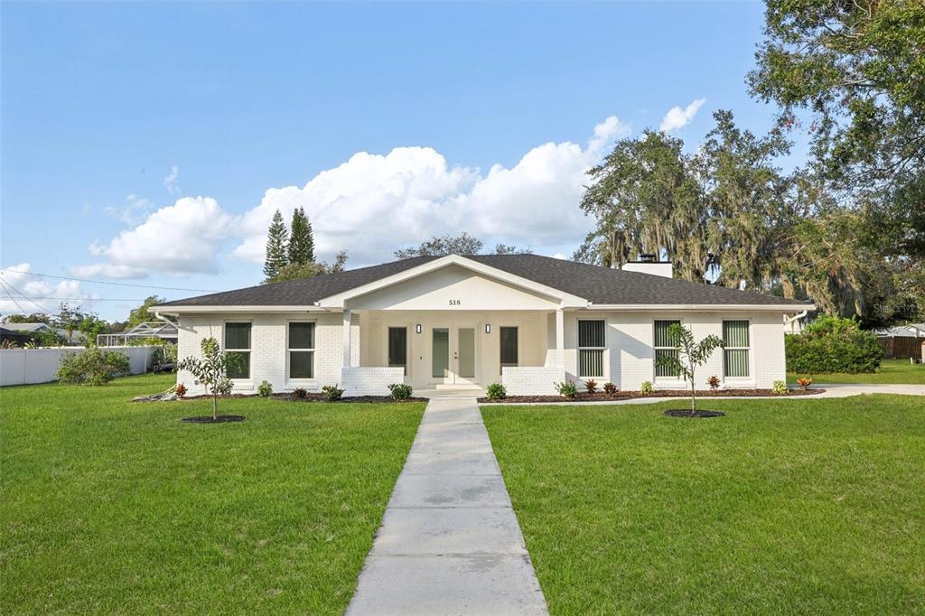 a front view of a house with a garden and trees