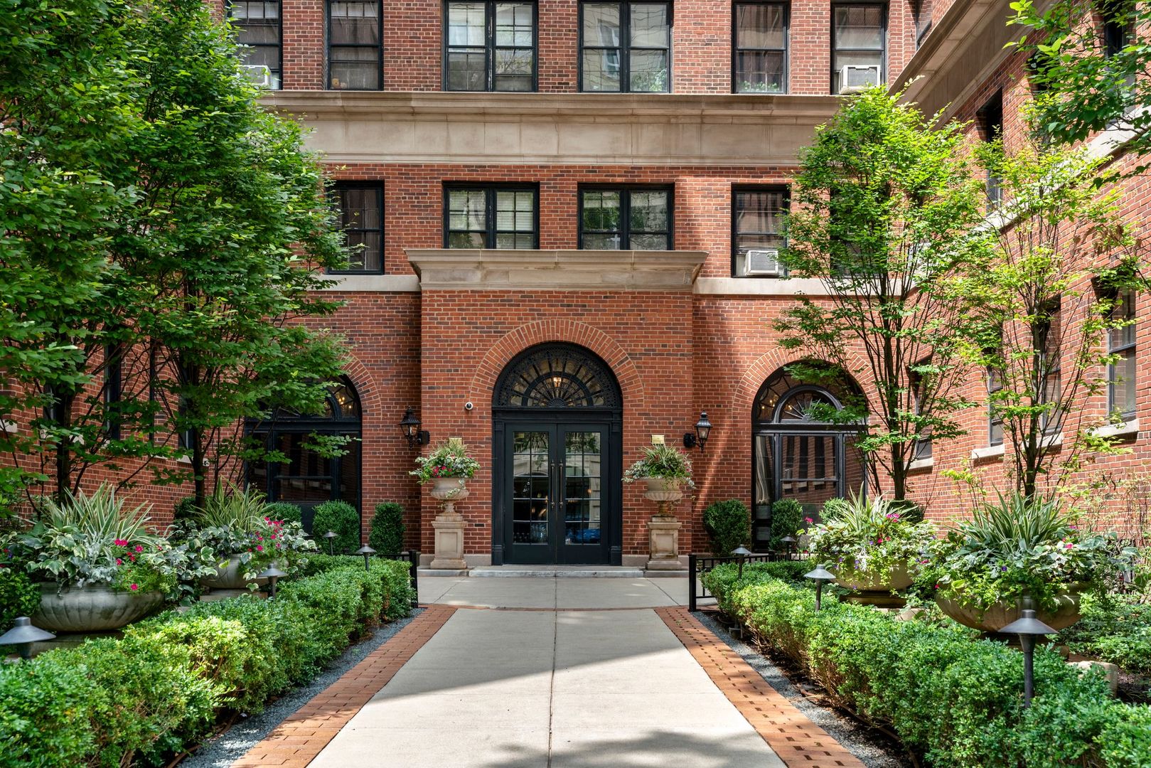 a view of a brick house with plants and large tree