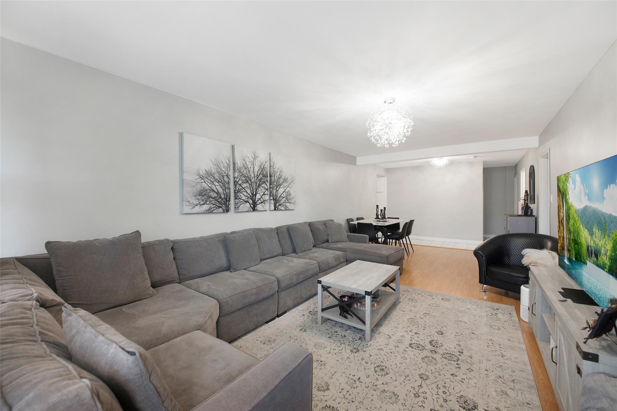 Living room with light hardwood / wood-style floors and a notable chandelier