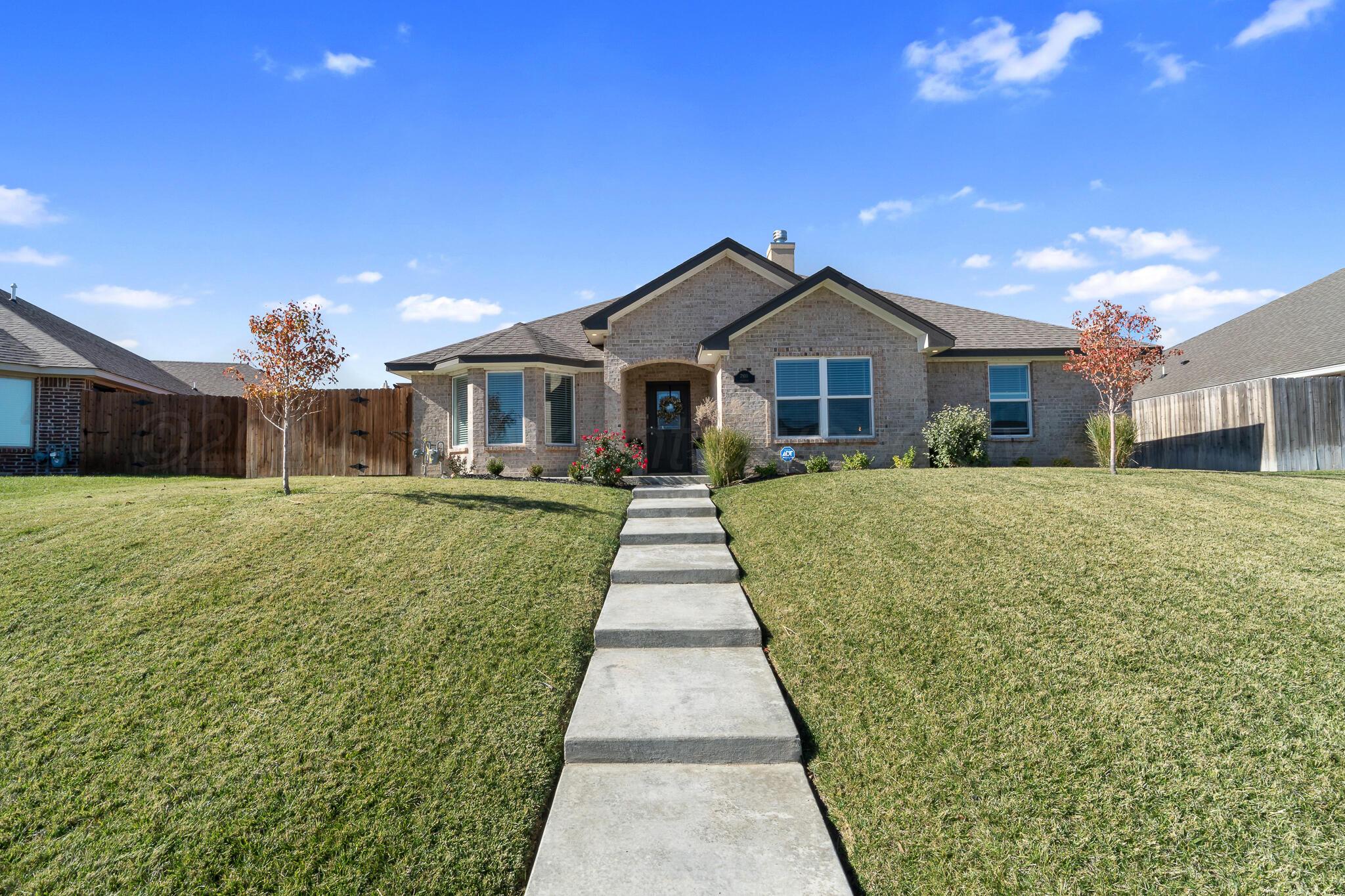 a front view of a house with a yard and potted plants